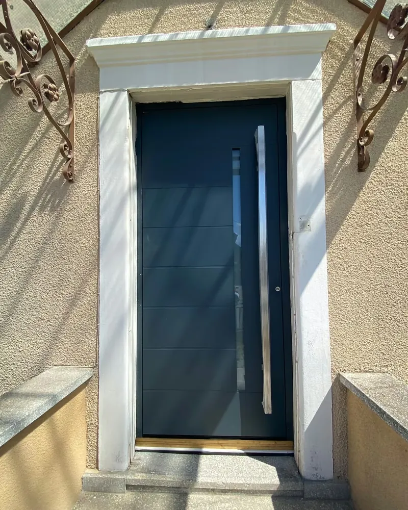 Porte d’entrée anthracite à longue poignée verticale, après la pose — photo de chantier