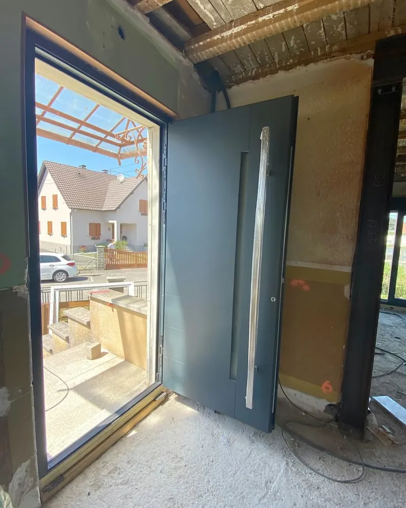 Pendant les travaux : la porte d’entrée anthracite ouverte, vue de l’intérieur — photo de chantier